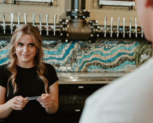 female server looking skeptically at a customer while holding an ID
