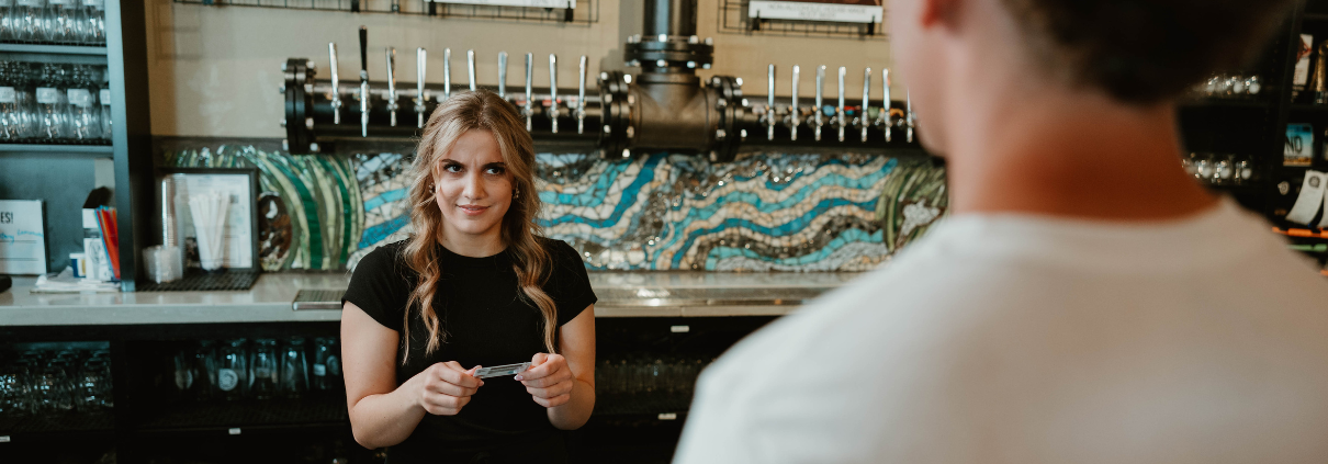 female server looking skeptically at a customer while holding an ID
