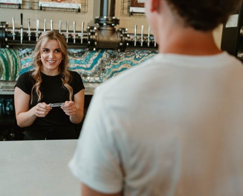 female bartender smiling and holding ID